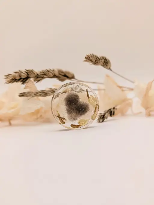 Porte clés rond en résine époxy avec incrustation de poils de popeye en forme de coeur et fleurs séhcé de muguet